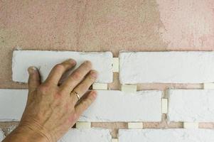 the employee's hand presses the decorative tiles against the finishing wall on the mortar. tile laying technology. photo