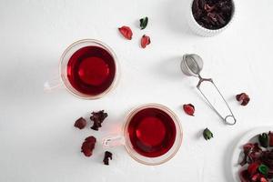 two modern glass cups of hibiscus or hibiscus tea on a white background with dried flowers. organic tea rich in vitamins and amino acids. photo