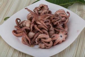 pulpo hervido en el plato y fondo de madera foto