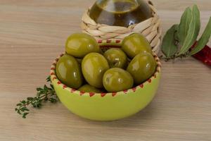 Green olives in a bowl on wooden background photo