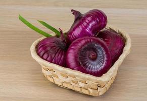 Violet onion in a basket on wooden background photo
