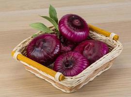 Violet onion in a basket on wooden background photo