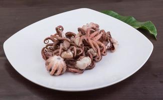 Boiled octopus on the plate and wooden background photo