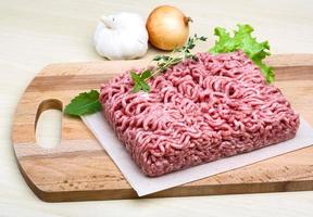 Minced meat on wooden board and wooden background photo