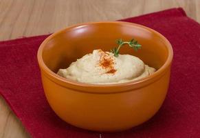 hummus en un recipiente sobre fondo de madera foto