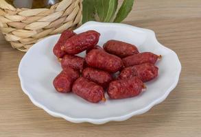 Mini salami on the plate and wooden background photo