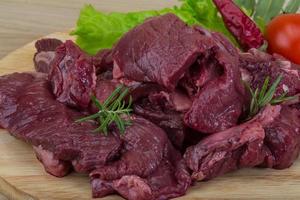 Raw venison on wooden board and wooden background photo