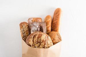 A variety of fresh delicious bread in a paper bag with handles on a white background. the concept of shopping without waste. photo