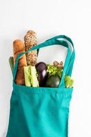 The eco-friendly shop- bag is filled with organic vegetables and products on a white background. The concept shopping in the supermarket. photo