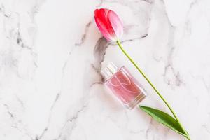 Lovely women's perfume in a glass spray bottle on a marble background with tulip. top view, a copy of the space for your text photo