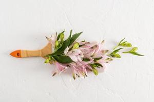 Beautiful spring flowers alstroemerieae in a composition with a brush. creative floral coloring. top view. white background. photo