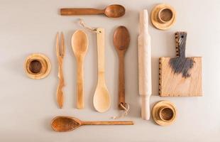 a set of various wooden spoons, cups and a cutting board on a light background. top view. flat styling. kitchen background. photo