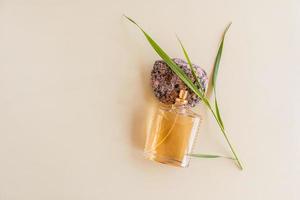 the original bottle of perfume or toilet water lies on a granite stone with a green blade of grass. top view. beige background. a copy of the space. photo