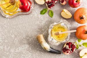 a silver bowl of honey, pomegranate, apples and a horn on a gray concrete background. festive composition New Year Rosh Hashanah. photo