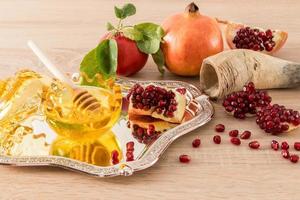 a silver tray with a bowl of honey and a pomegranate. ripe fruits and a cornucopia on a wooden background. roshhashan holiday, the Jewish new year. photo