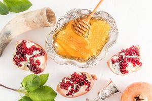 a silver bowl of honey on a festive table among a broken delicious pomegranate. symbols of the Jewish New Year Roshashan. top view. photo