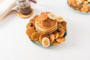 an assortment of pancakes on a plate, chocolate paste in a jar on a white table. delicious breakfast for children. white background. photo