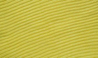 Texture of smooth knitted yellow sweater with pattern. Top view, close-up. Handmade knitting wool or cotton fabric texture. Background of knitting patterns. photo