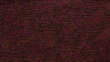 Texture of smooth knitted red brown sweater with pattern. Top view, close-up. Handmade knitting wool or cotton fabric texture. Background of knitting patterns front and back stitch. photo