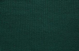 Texture of smooth knitted dark green sweater with pattern. Top view, close-up. Handmade knitting wool or cotton fabric texture. Background of Large Ribs knit pattern with knitting needles or crochet. photo