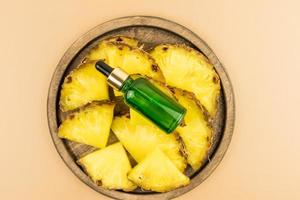 face serum with pineapple extract or moisturizing cosmetic oil on a wooden tray with juicy fruit slices. top view. photo