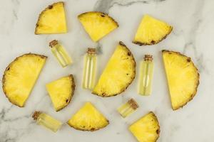 cosmetic background. slices of ripe juicy pineapple and bottles with a cork lie on a marble surface. the concept of natural cosmetics. photo