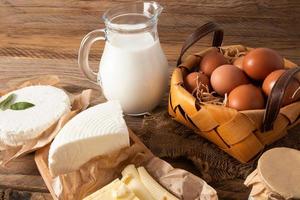 a set of fresh high-protein products on a wooden table. a jug of milk, an egg basket, homemade cheese and cottage cheese. country life. photo