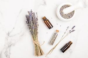 medicinal lavender flowers and essential oil in medical bottles on a marble table. top view. flat styling. natural medical cosmetics. photo