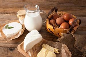 natural farm products on the village table. a jug of sipped milk, a basket of eggs, cheese, butter on the board. photo