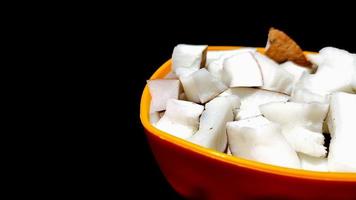 Fresh coconut pieces in a bowl on dark color background photo