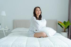 A beautiful woman sitting on a pillow in her bedroom, smiling, laughing happily. photo