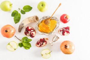 top view of the white background with traditional Symbols New Year Rosh Hashanah. yaboki, pomegranate, honey in a silver bowl, horn. flat layout. photo