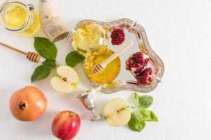 top view of a silver tray with a bowl of honey and pomegranate and ripe apples on a white background. New Year Holiday Rosh Hashanah. photo