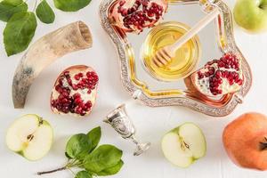 festive background with traditional symbols of New Year Rosh Hashanah. pomegranate, apples, honey in a silver bowl, a cornucopia. top view. photo