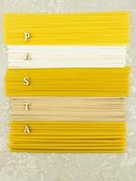 vista superior plana vertical de varias pastas secas italianas sobre un fondo gris. letras de madera con la palabra -pasta. foto