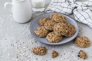 dark ceramic plate with homemade oatmeal cookies on a gray background with a jug of milk. healthy dietary food. photo