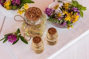 glass bottles with natural St. John's wort oil of white wooden boards and St. John's wort herb. an ideal remedy for problem skin of the face. photo