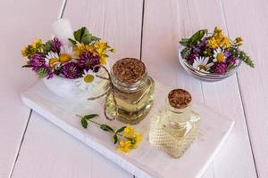 beautiful glass bottles with natural oils of meadow healing plants on a white wooden podium. organic self-care. selective focus. photo