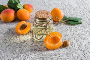 vista frontal de botellas de vidrio con albaricoque entre los albaricoques. el concepto de rejuvenecimiento, nutrición e hidratación de la piel. foto