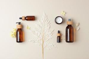 composición cosmética con productos cosméticos para el cuidado de la piel y flores sobre fondo beige pastel. endecha plana, espacio de copia foto