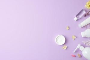 productos cosméticos para el cuidado de la piel con flores sobre fondo rosa. endecha plana, espacio de copia foto