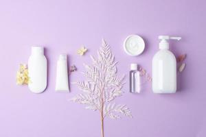 composición cosmética con productos cosméticos para el cuidado de la piel y flores sobre fondo rosa. endecha plana, espacio de copia foto