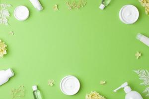 productos cosméticos para el cuidado de la piel con flores sobre fondo verde. endecha plana, espacio de copia foto
