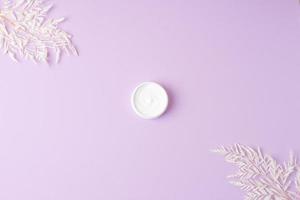 Jar of cosmetic cream with flowers on rose background. Flat lay, copy space photo