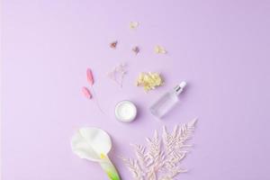 Cosmetic skin care products with flowers on rose background. Flat lay, copy space photo