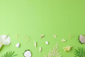 Cosmetic background with flowers, moss and stone on green. Flat lay, copy space photo