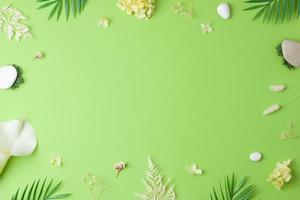 Cosmetic background with flowers, moss and stone on green. Flat lay, copy space photo