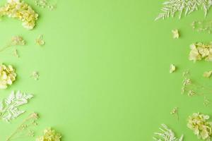 Cosmetic background with flowers on green. Flat lay, copy space photo