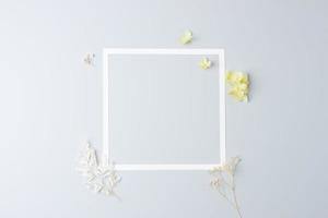 Cosmetic background with flowers and white frame on grey. Flat lay, copy space photo
