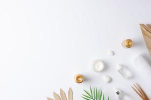 Spa treatment with cosmetic bottle, candles and palm leaf on white background. Flat lay, copy space photo